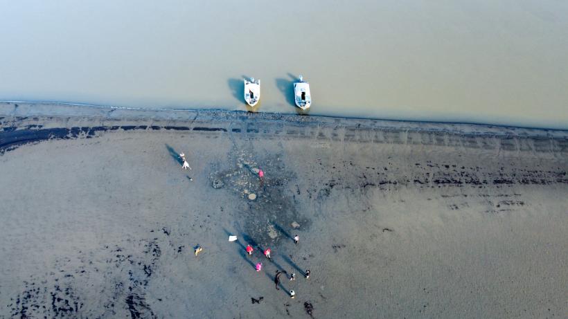 Luftaufnahme von einem Gewässer mit Booten und Personen